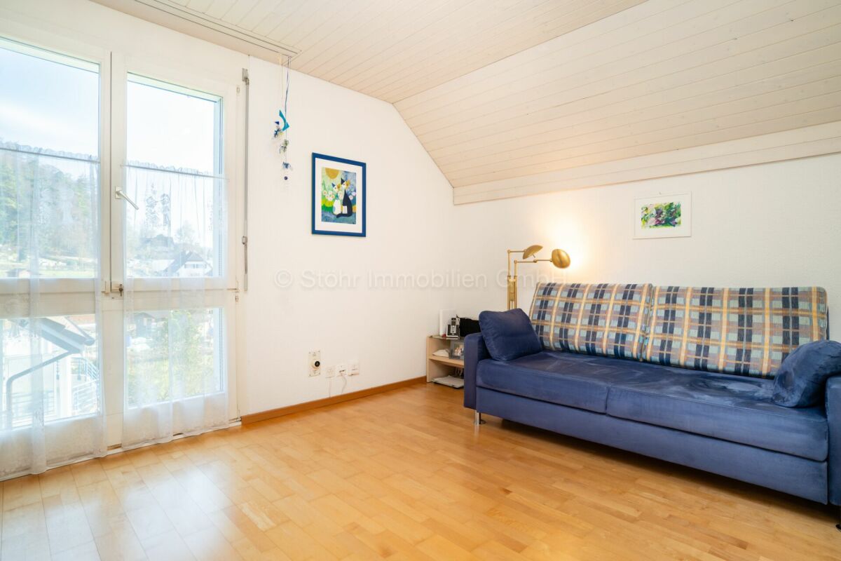 Helles Dachgeschoss-Wohnzimmer mit Sofa und großen Fenstertüren