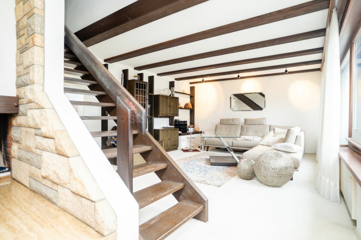 Wohnzimmer mit Holztreppe und sichtbaren Deckenbalken