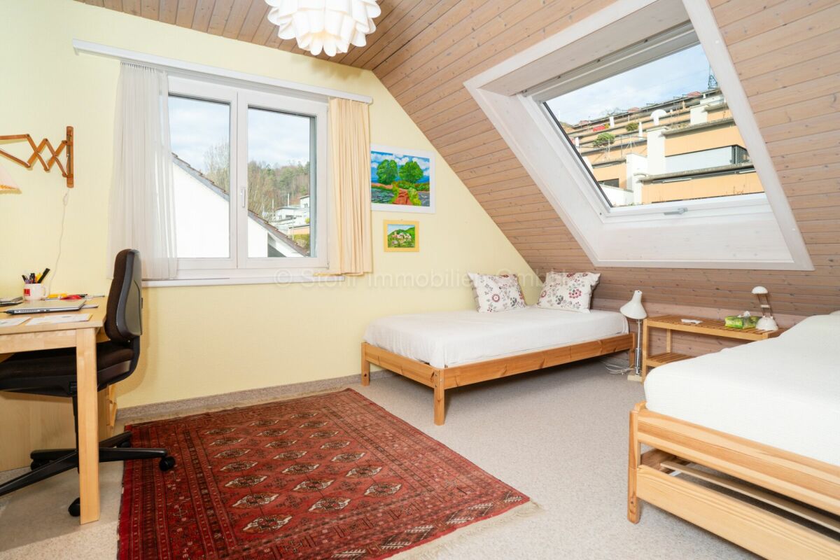 Dachzimmer mit zwei Betten und Schreibtisch