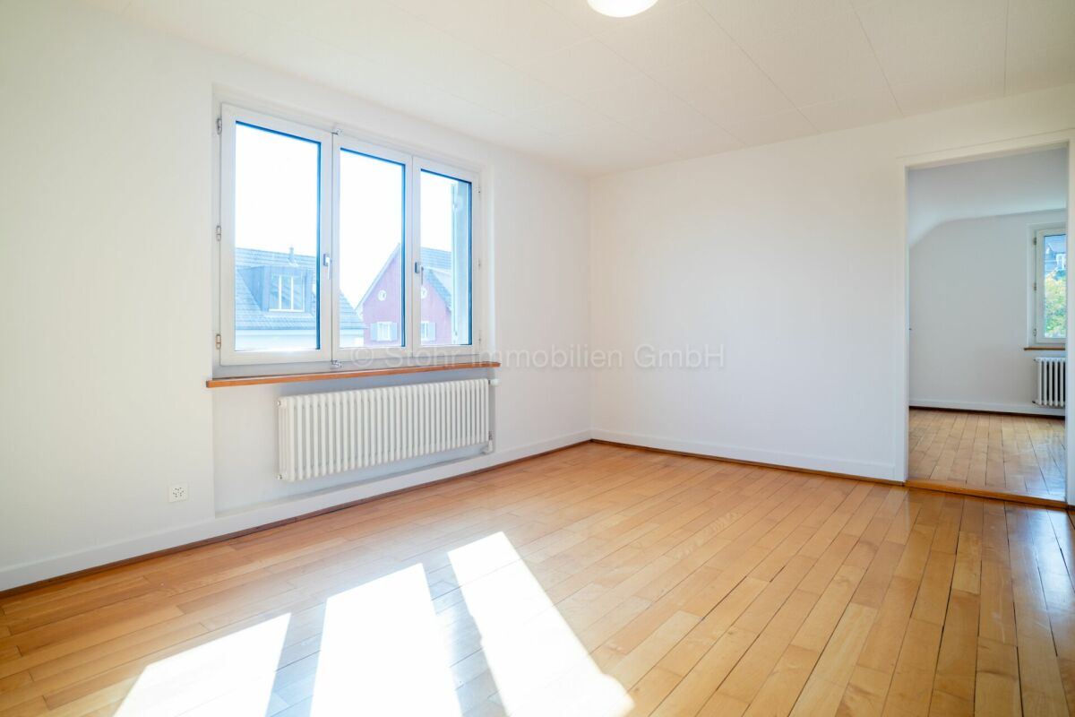 Heller leerer Wohnraum mit Parkett und Fenster