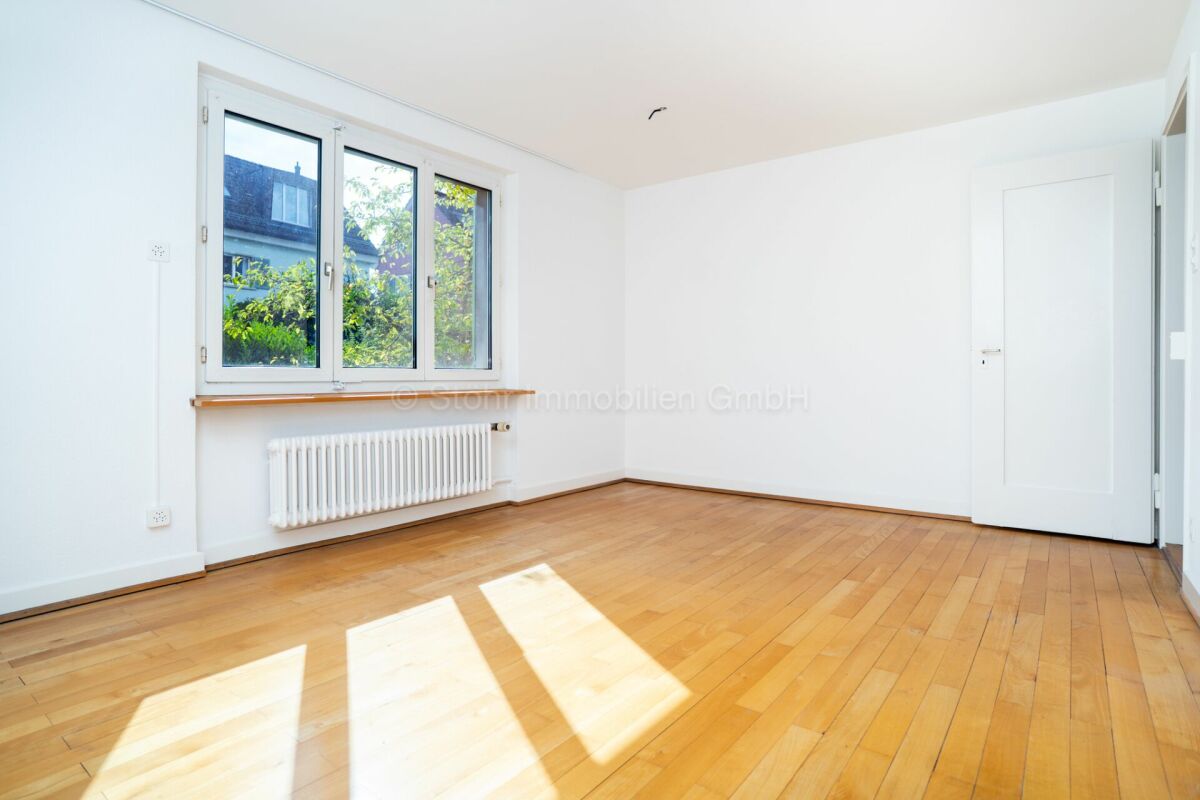 Helles, leeres Zimmer mit Parkett und Fenster