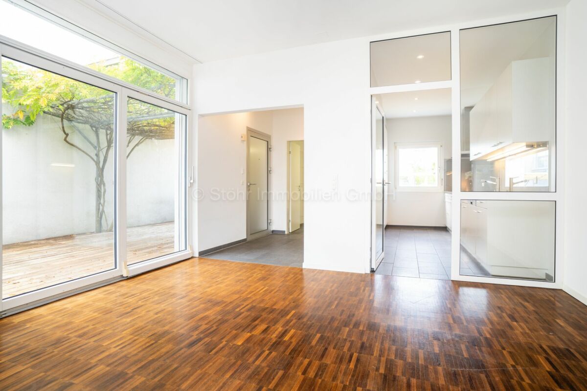 Heller Wohnraum mit großer Glasfront und Zugang zum Innenhof