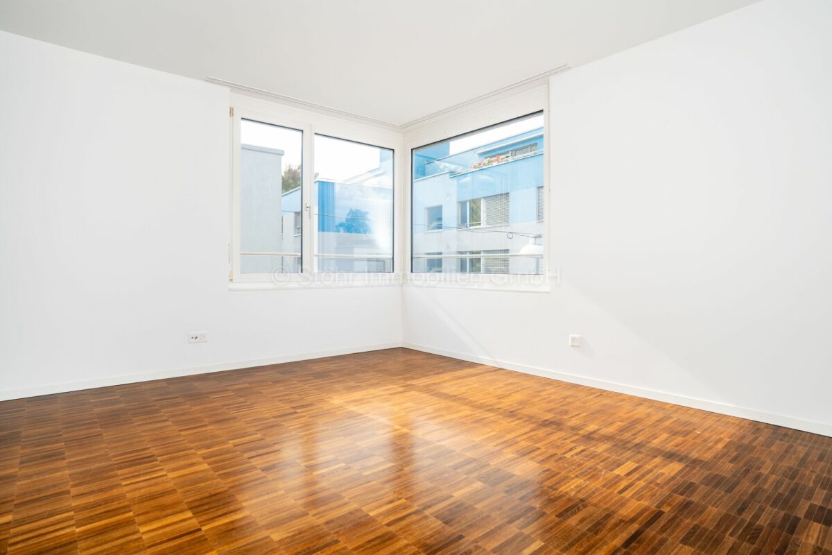 Leerer heller Raum mit Holzfußboden und großen Fenstern
