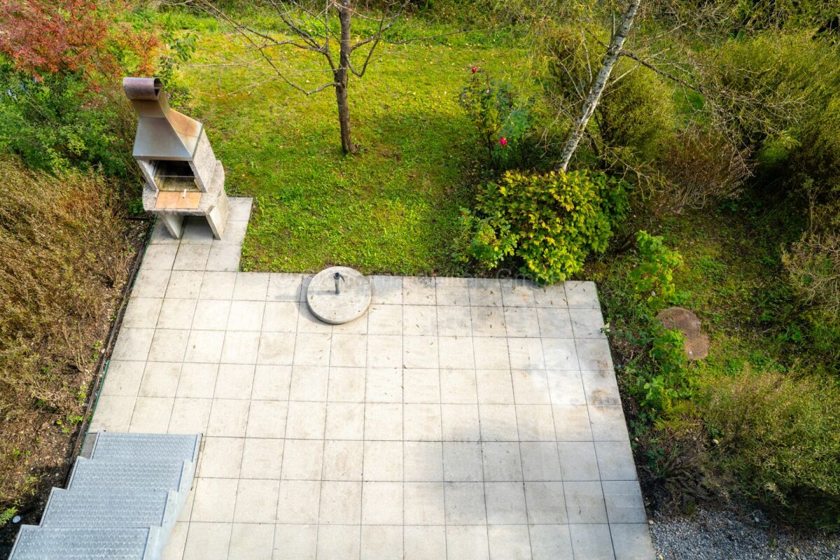 Außenansicht einer gepflasterten Garten- und Terrassenfläche mit Grill