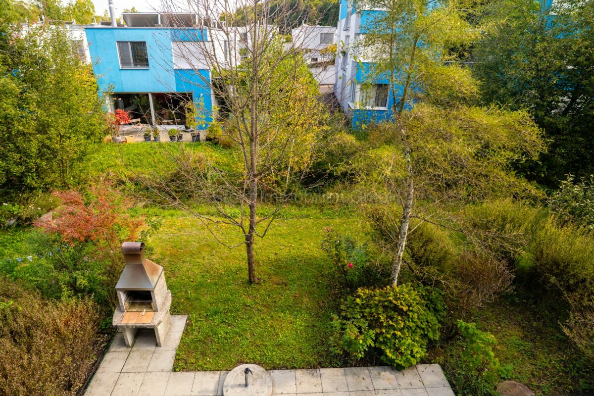 Garten mit Außengrill vor modernem Wohnhaus