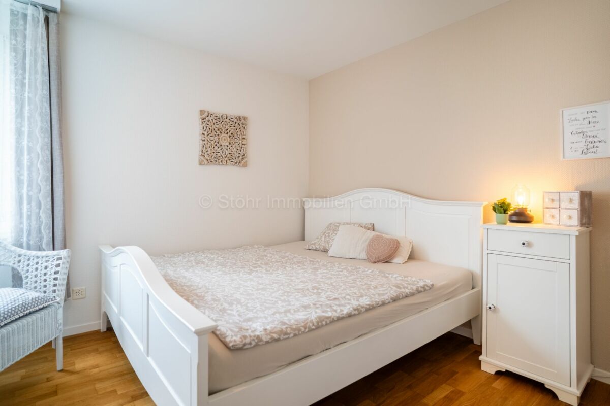 Helles Schlafzimmer mit weißem Bett und Nachttisch