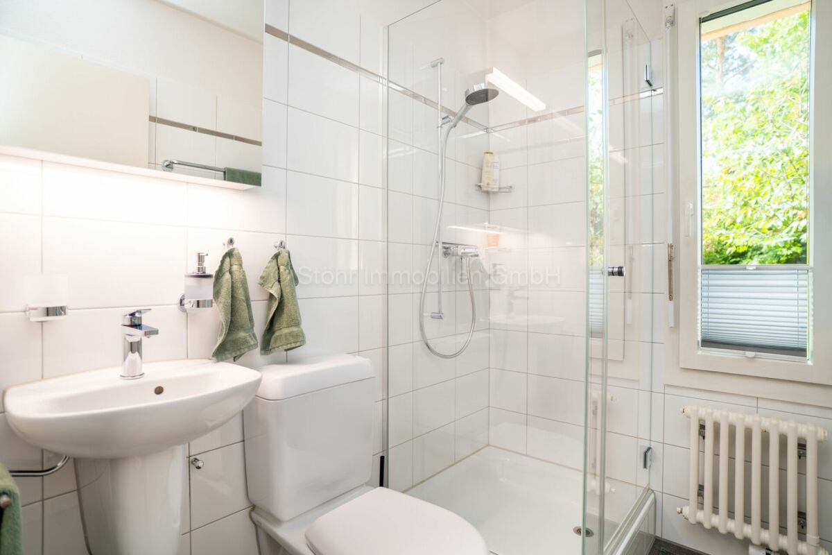 Helles Badezimmer mit Dusche, Waschbecken und Fenster