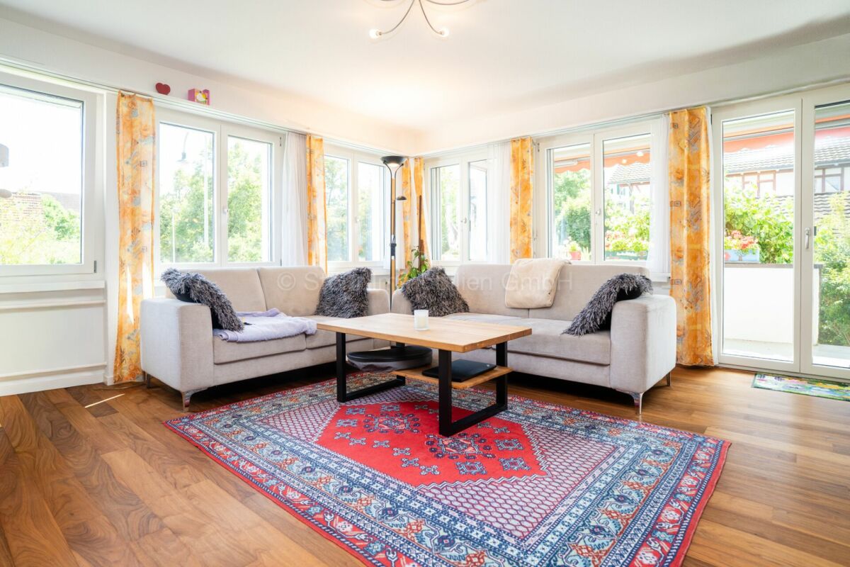 Heller Wohnraum mit Ecksofa und großen Fenstern
