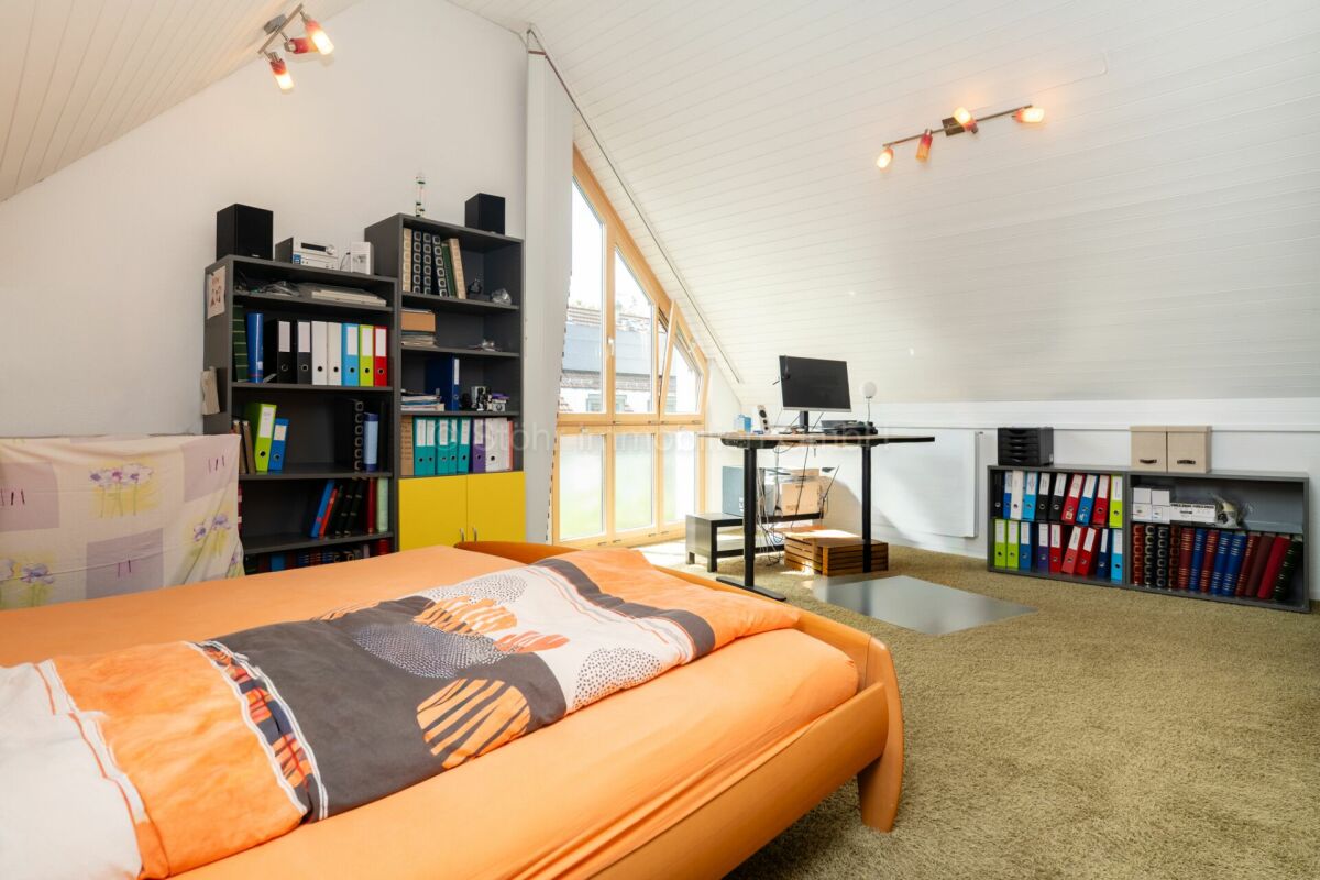 Ausgebautes Dachzimmer mit Bett und Arbeitsbereich