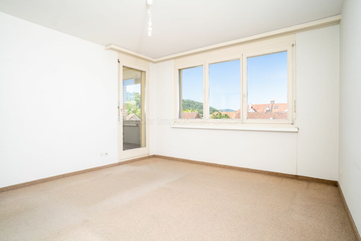 Heller leerer Wohnraum mit großem Fenster und Balkonzugang