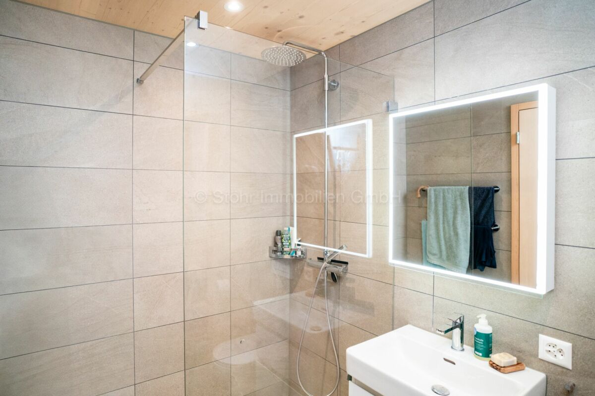 Modernes Badezimmer mit begehbarer Dusche und beleuchtetem Spiegel