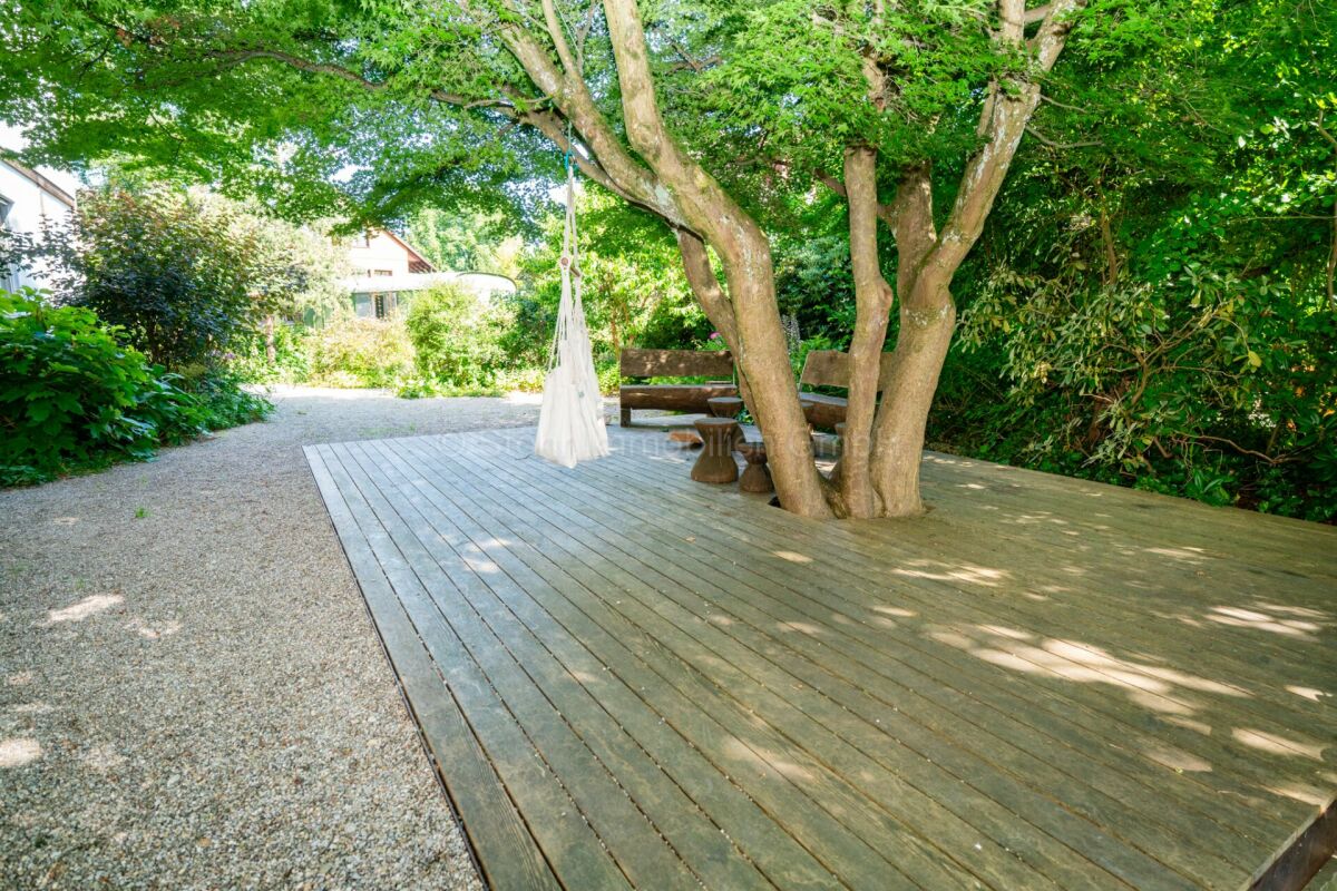 Gartenterrasse mit Holzdeck unter einem großen Baum