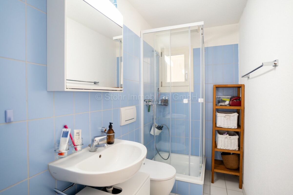 Hell gefliestes Badezimmer mit Dusche und Waschtisch