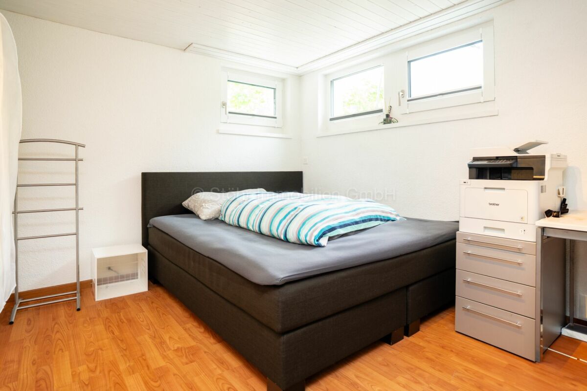 Schlichtes Schlafzimmer mit Bett und Arbeitsbereich