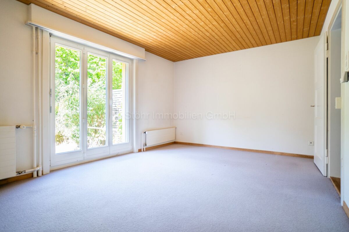 Leerer heller Raum mit Holzdecke und Terrassentür