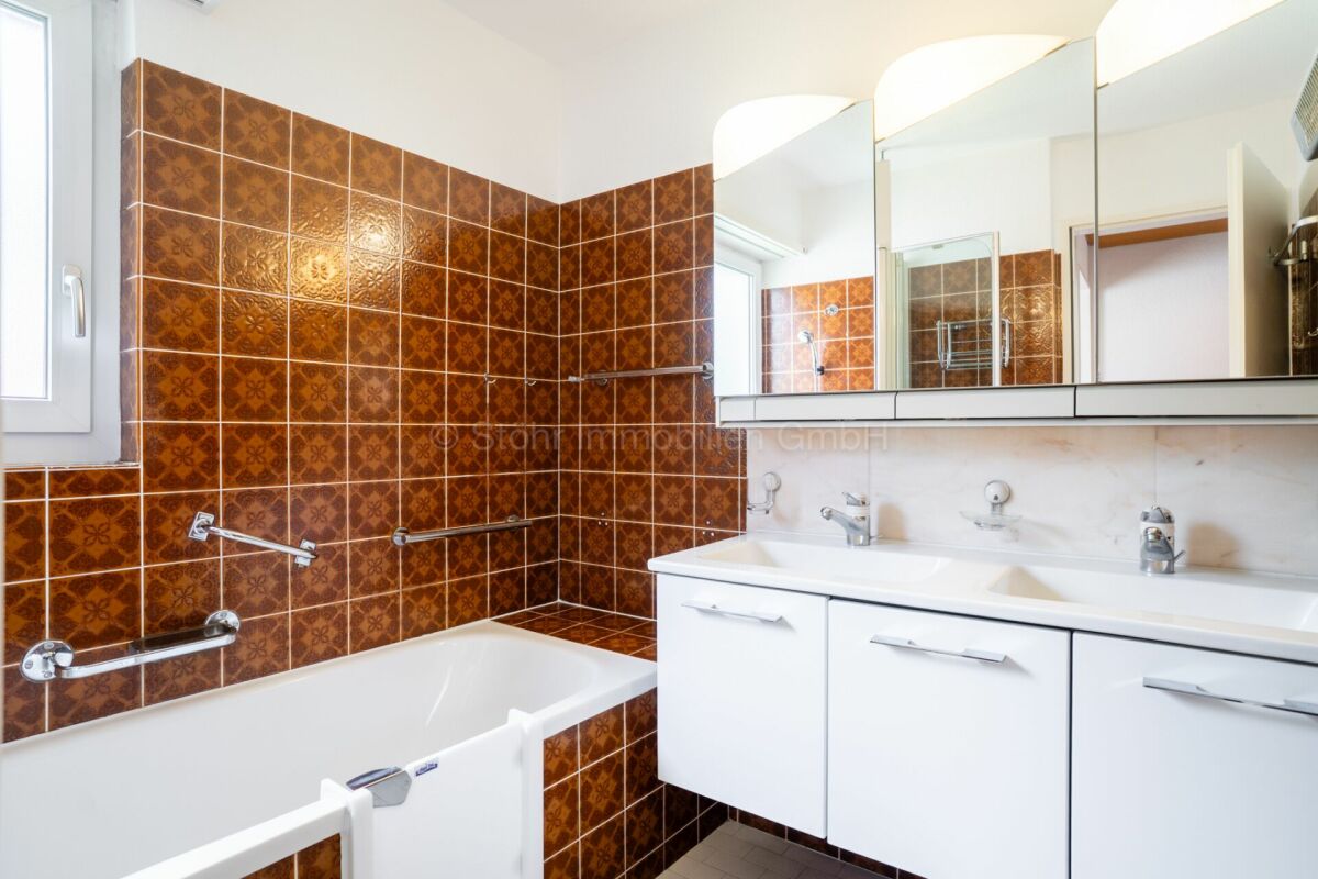 Badezimmer mit braunen Wandfliesen und Doppelwaschbecken