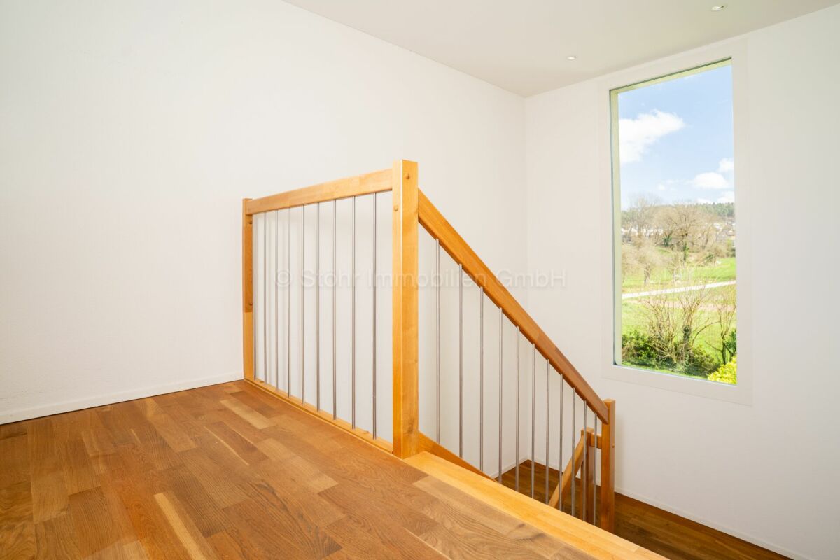 Treppenbereich mit Holzgeländer und Fensterblick