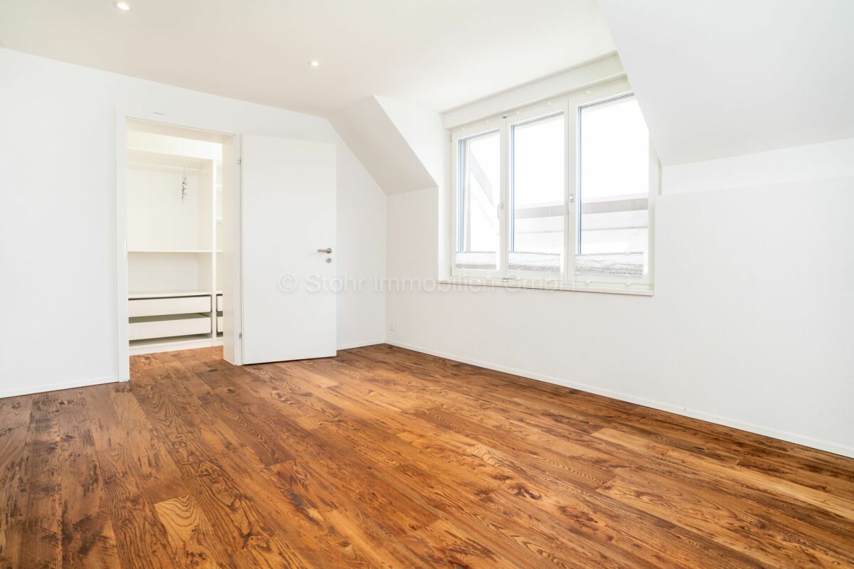 Helles leeres Dachgeschosszimmer mit Holzfußboden und Einbauschrank