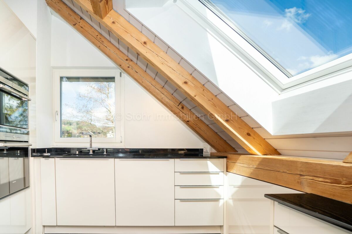 Helle Dachgeschossküche mit Dachfenster und Sichtbalken