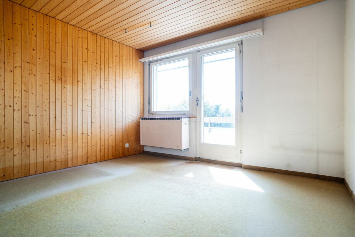 Leerer Wohnraum mit Holzdecke und Fensterfront
