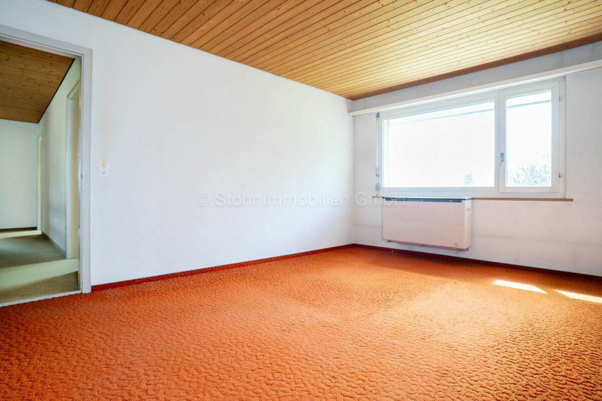 Leeres Zimmer mit Holzdecke und orangefarbenem Teppich