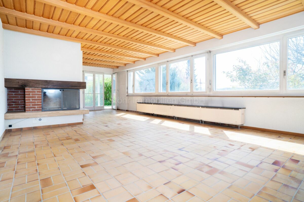 Heller Wohnraum mit Kamin und großen Fenstern
