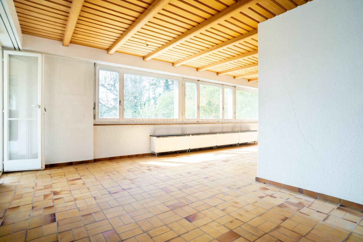 Heller Wohnraum mit Holzdecke und großen Fenstern