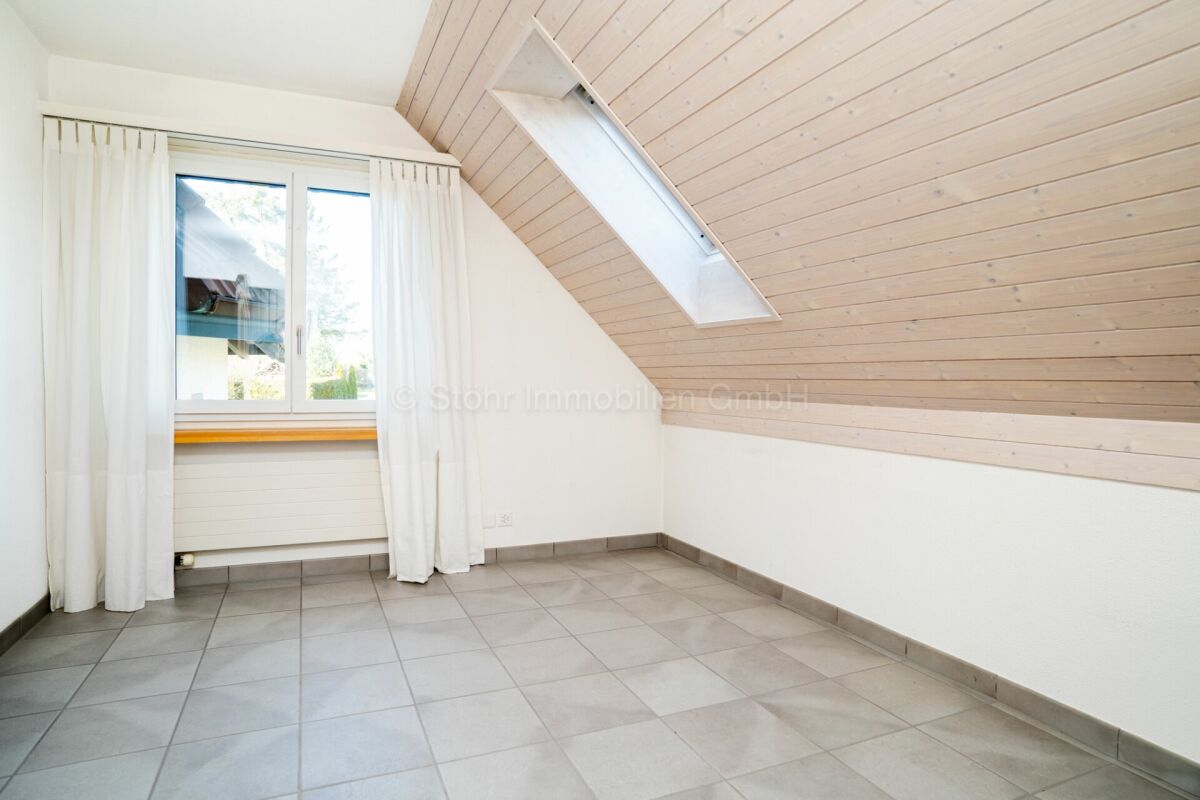 Helles Dachgeschosszimmer mit Fenster und Dachschräge