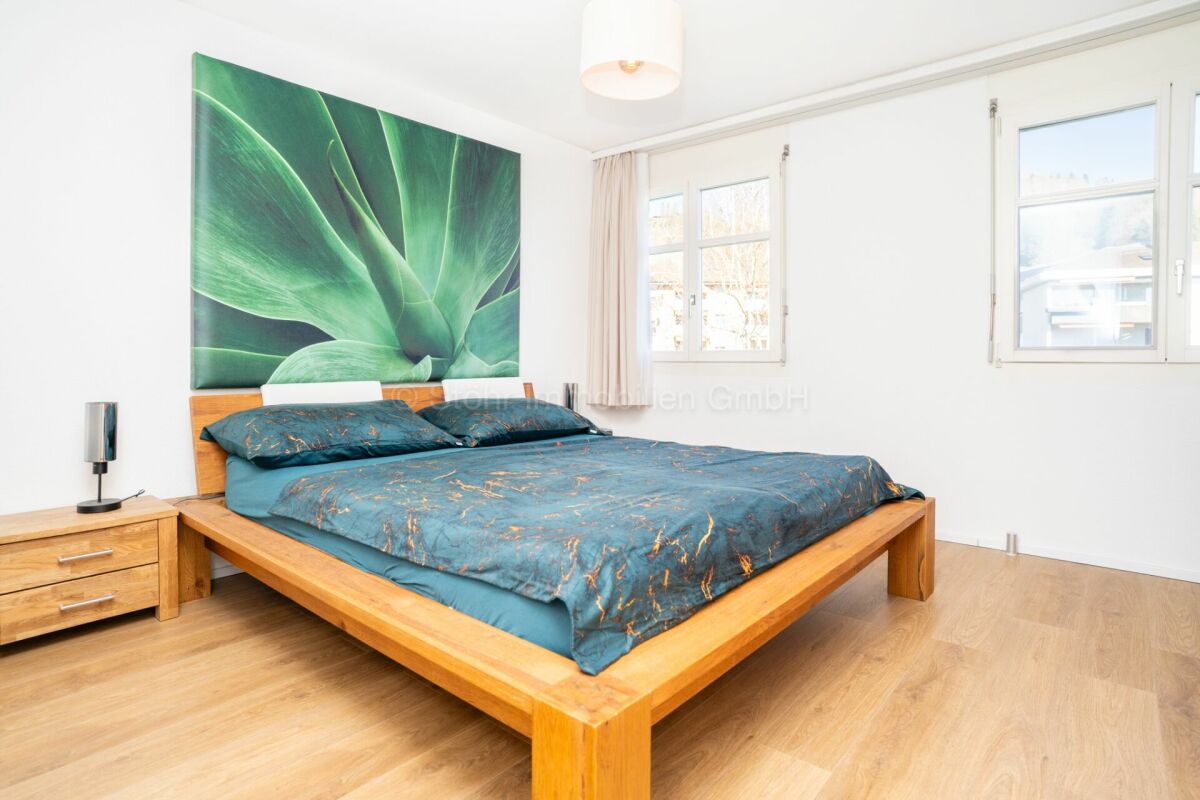 Helles Schlafzimmer mit Holzbett und großem Wandbild