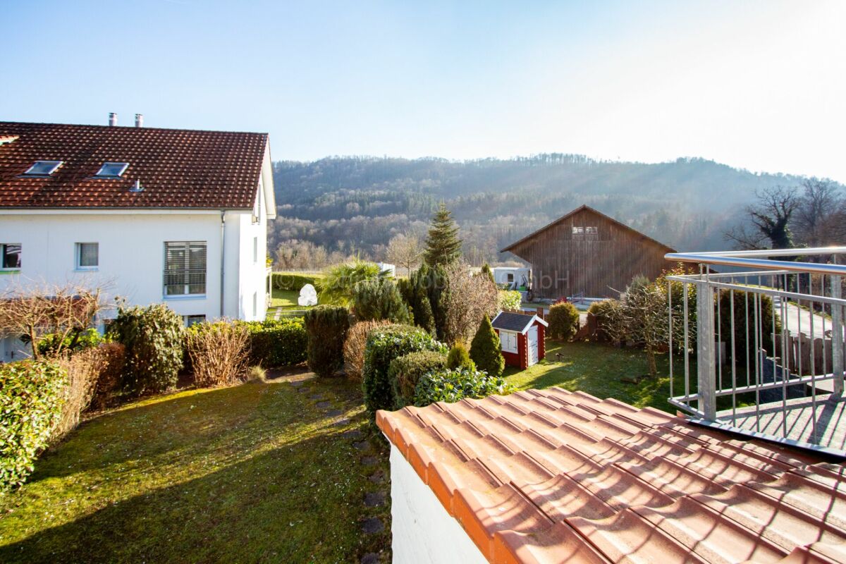 Gartenblick mit Haus, Balkon und Bergpanorama