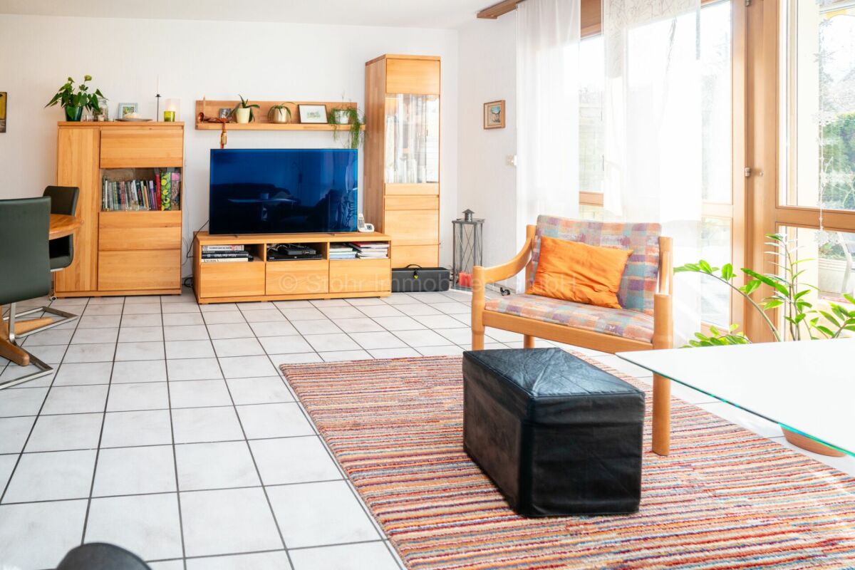 Helles Wohnzimmer mit großen Fenstern und Holzmöbeln
