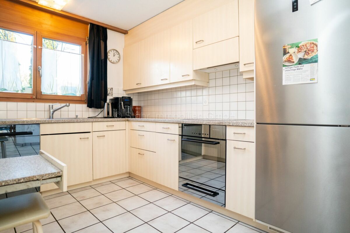Helle Einbauküche mit Holzfenster und Edelstahlkühlschrank