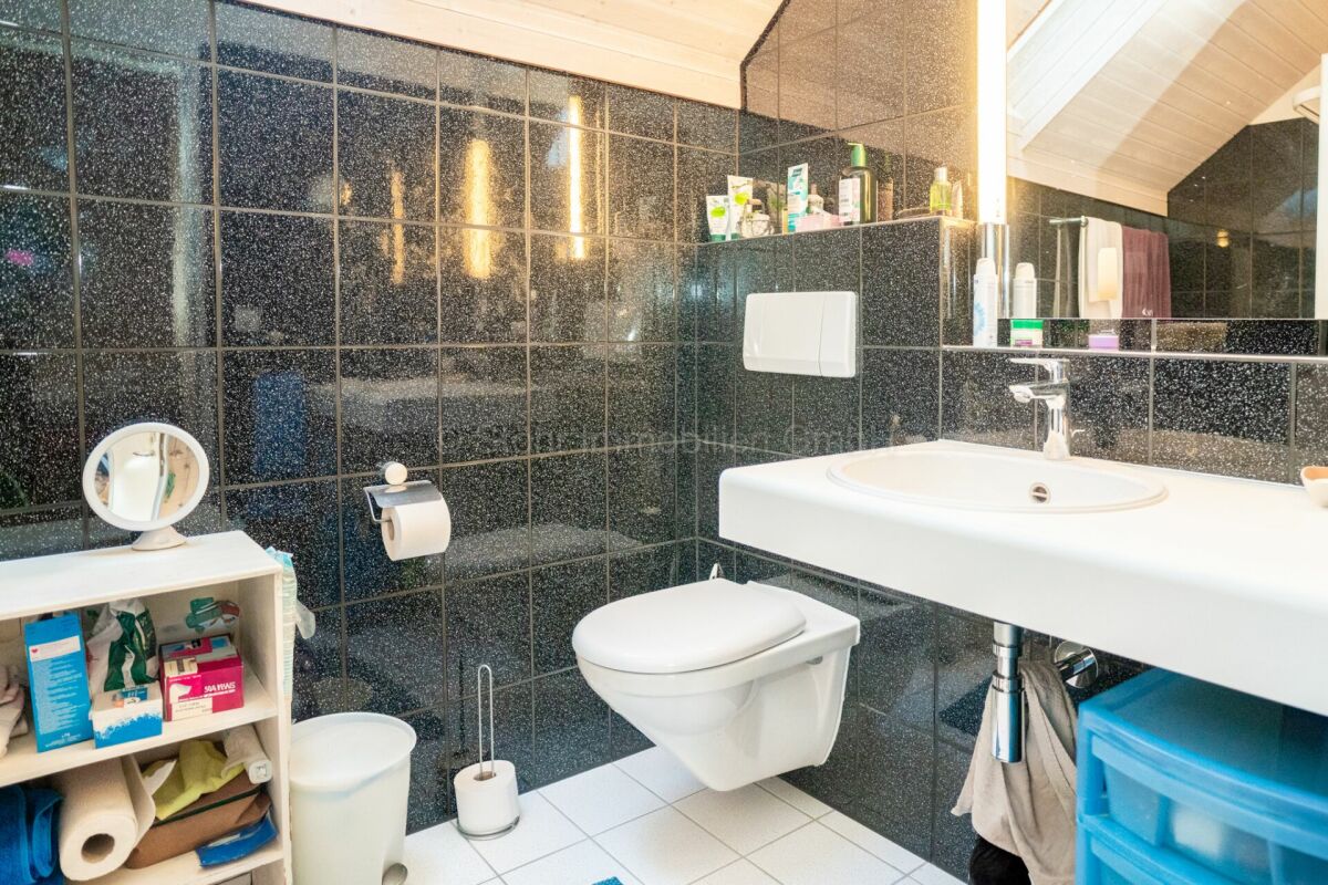 Modernes Badezimmer mit dunklen Fliesen und weißem Waschtisch