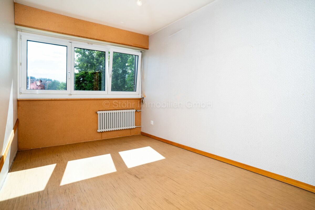 Leerer Wohnraum mit Fenster und Heizkörper