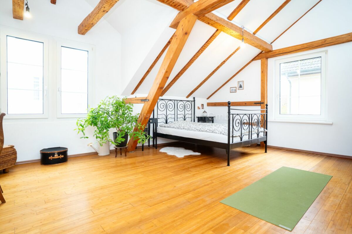 Dachgeschoss-Schlafzimmer mit sichtbaren Holzbalken