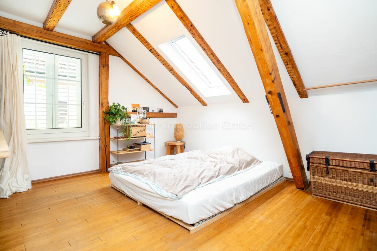 Dachgeschoss-Schlafzimmer mit sichtbaren Holzbalken