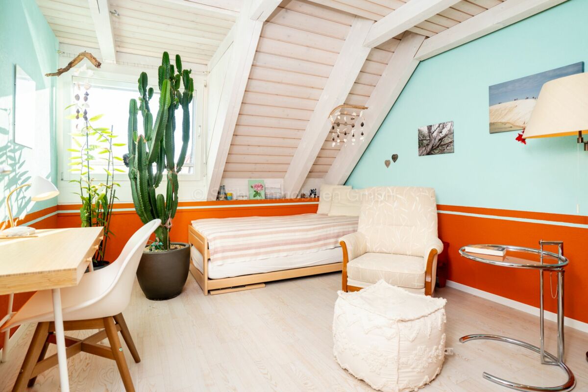 Helles Dachzimmer mit Bett und Sitzbereich