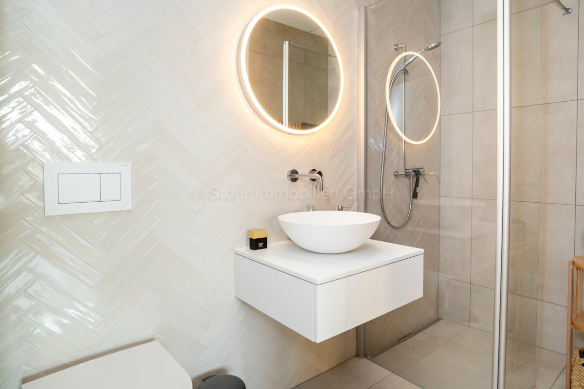 Modernes Badezimmer mit Walk-in-Dusche und beleuchtetem Spiegel