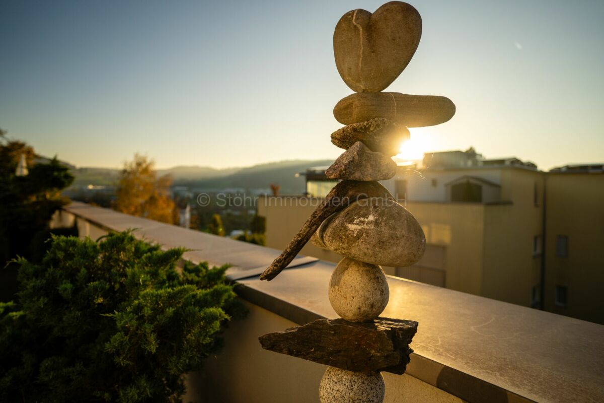 Rooftop-Terrasse mit Steinskulptur im Gegenlicht