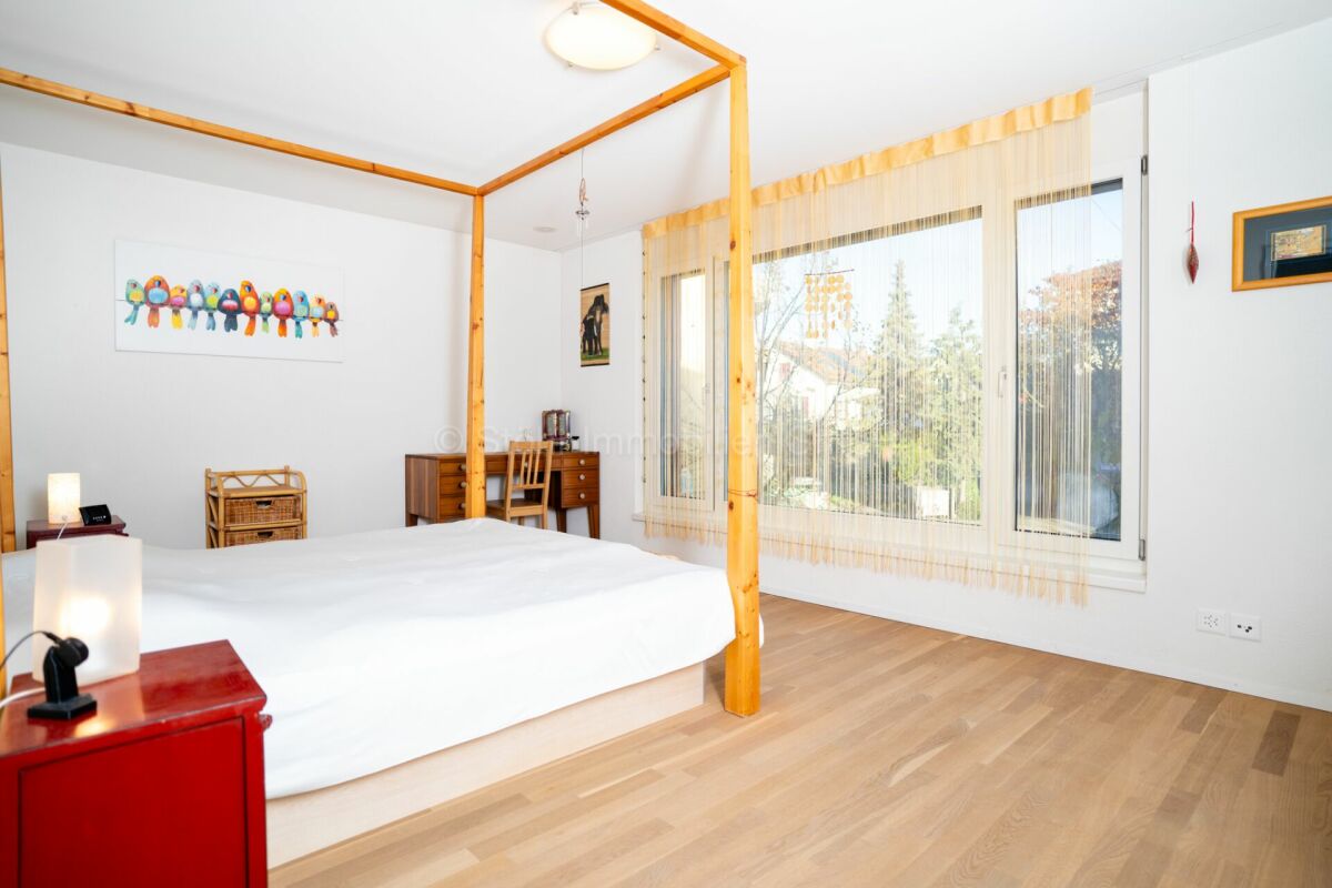 Helles Schlafzimmer mit Naturholzbett und großen Fenstern