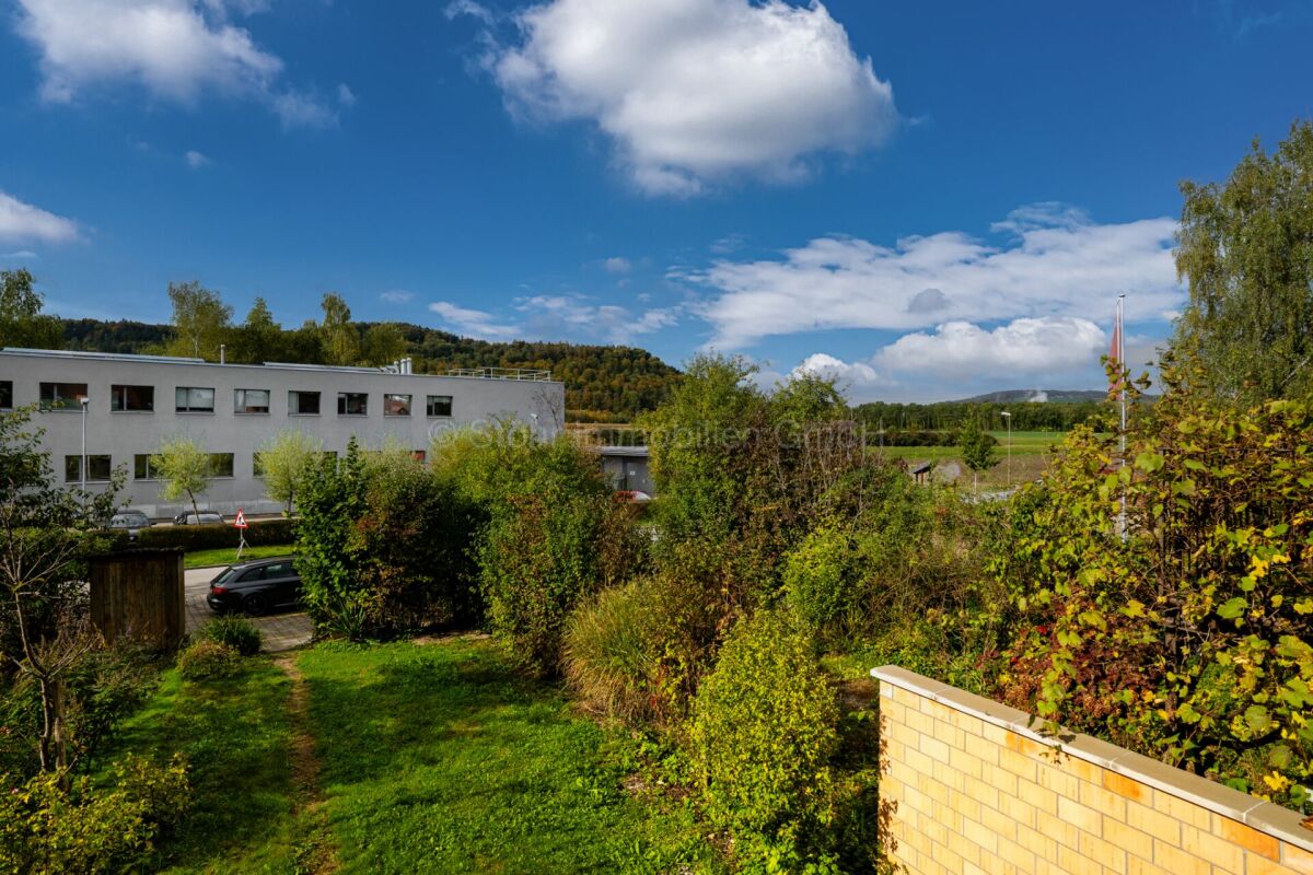 Blick ins Grüne mit Gebäude im Hintergrund