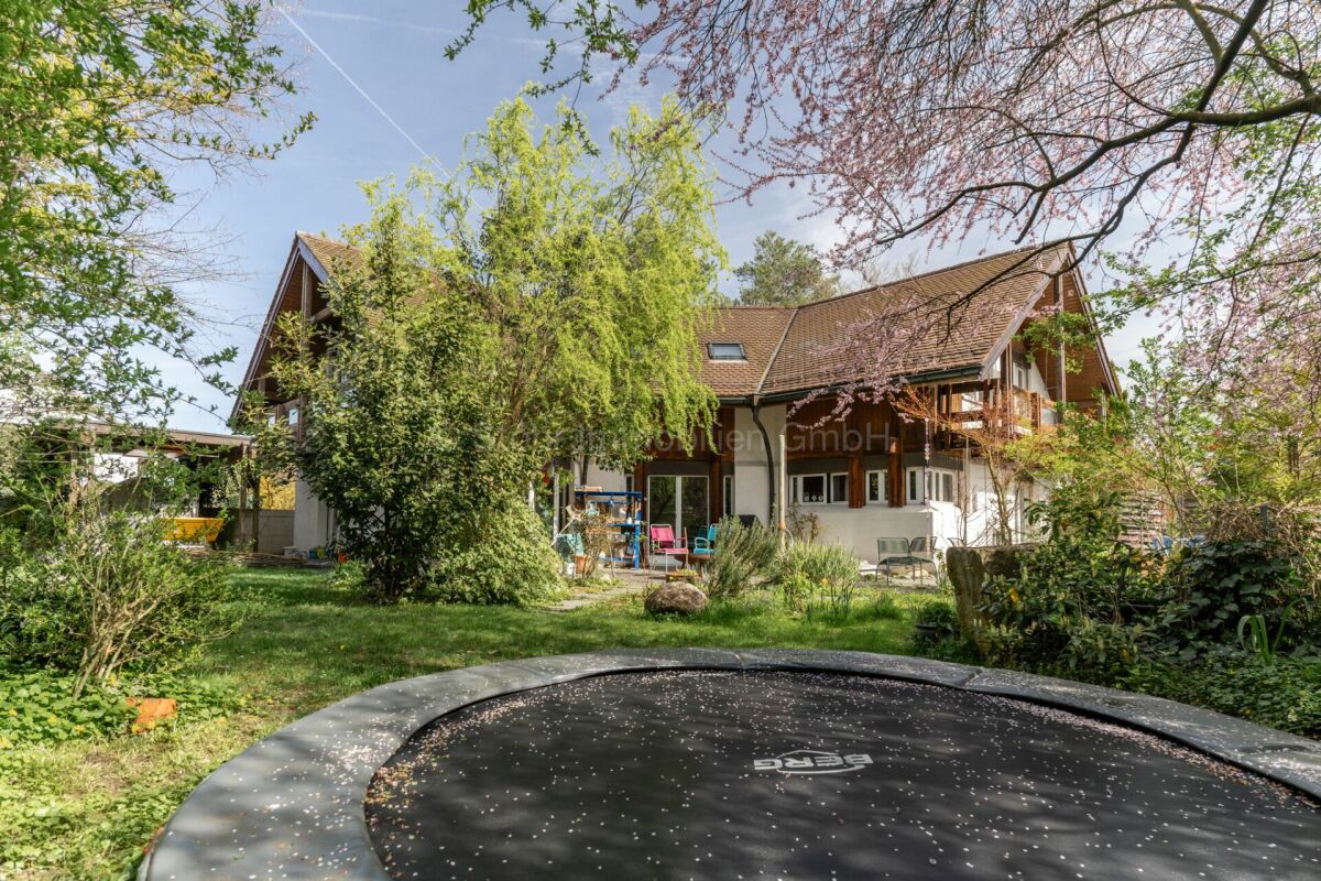 Gartenansicht eines großen Hauses mit Trampolin