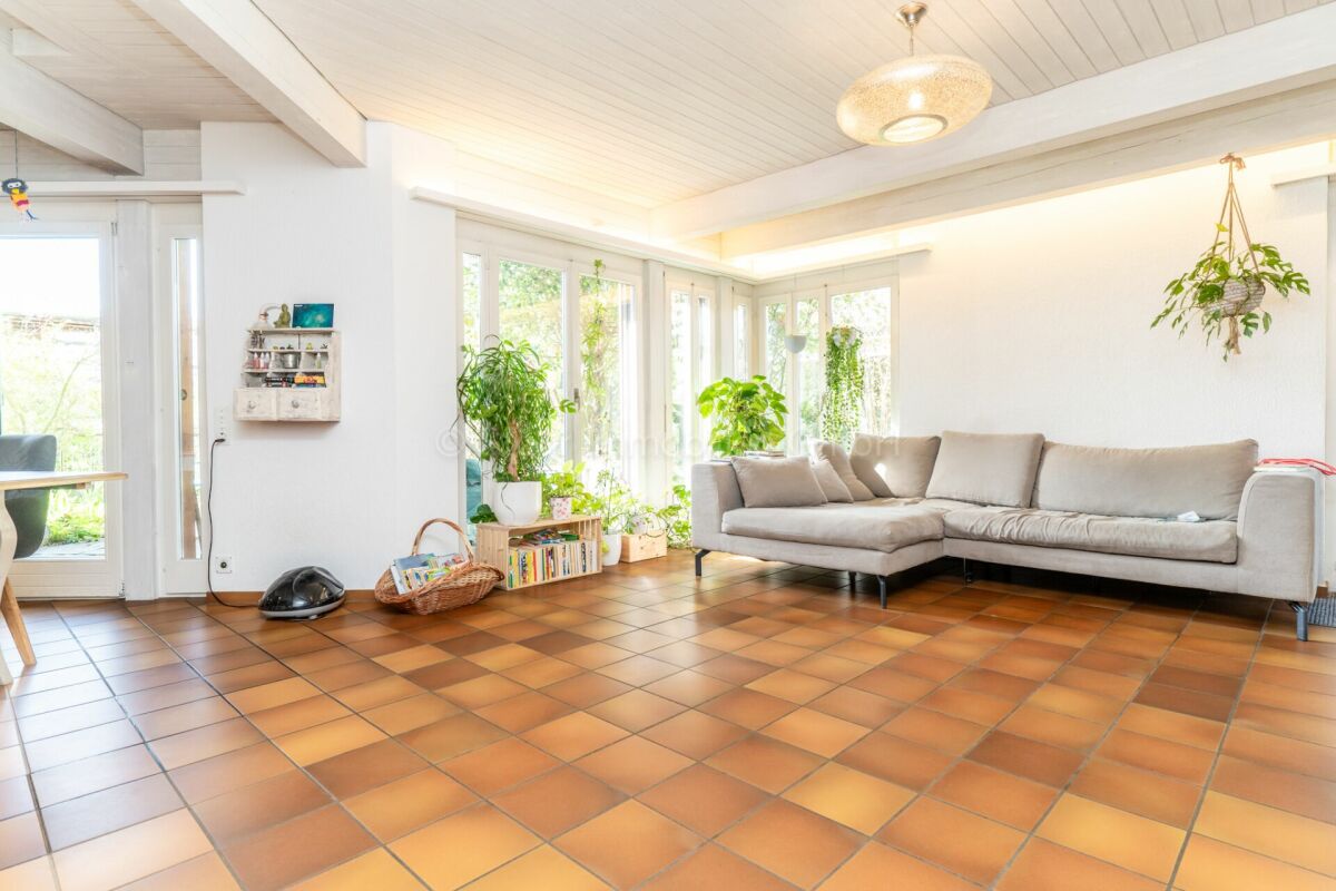 Heller Wohnraum mit Ecksofa und vielen Pflanzen