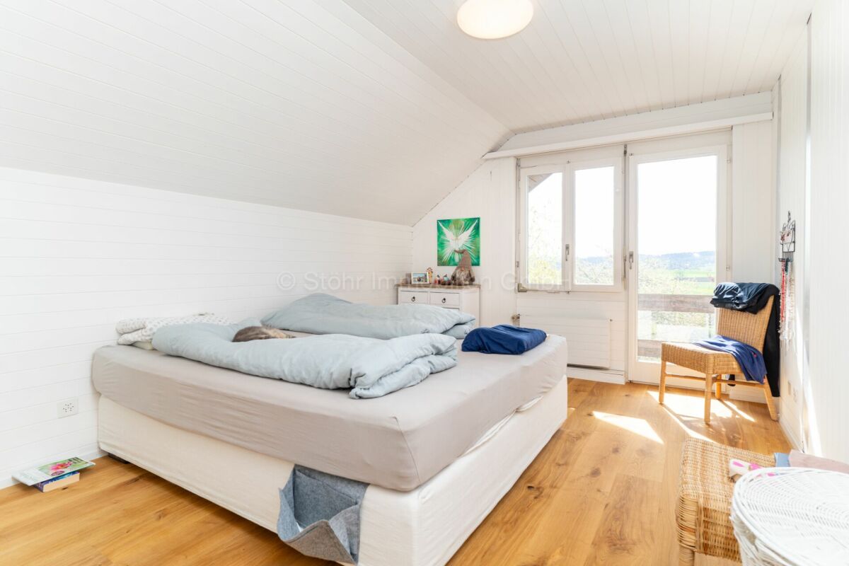 Helles Schlafzimmer mit Dachschräge und Blick ins Grüne