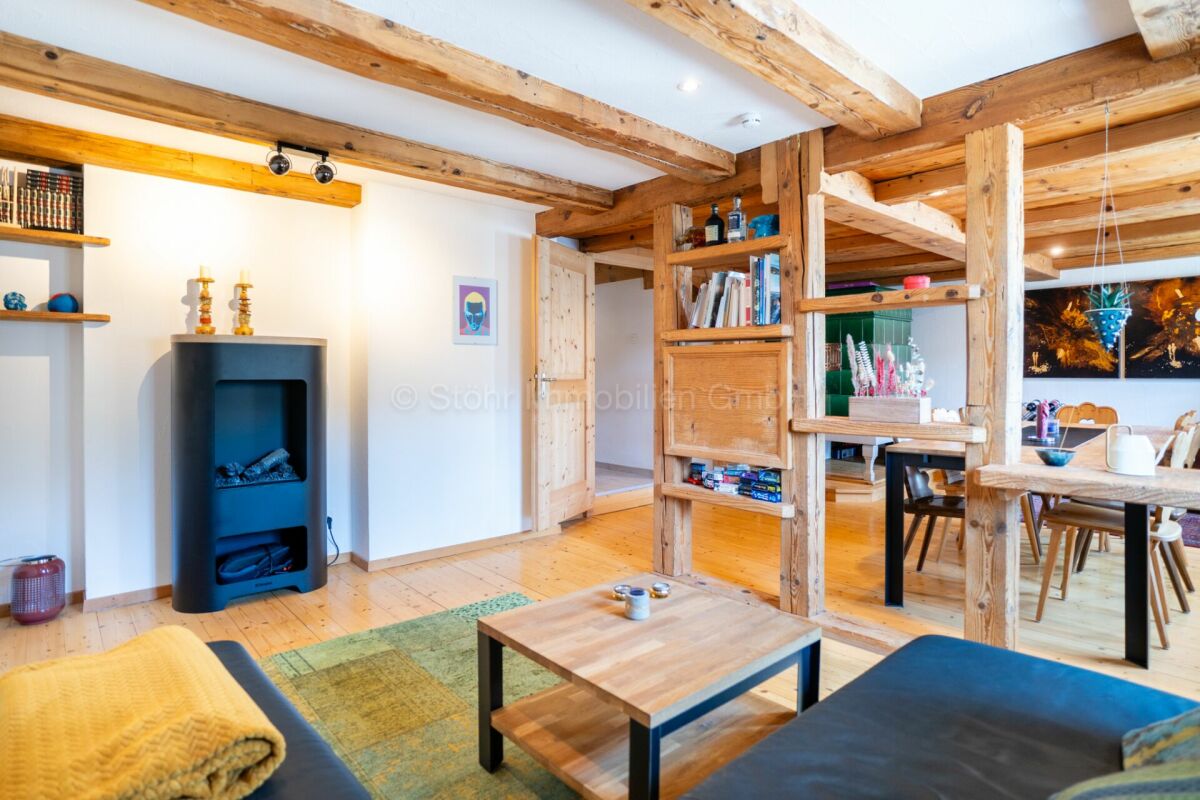 Gemütlicher Wohn-Essbereich mit Holzbalken und Holzofen