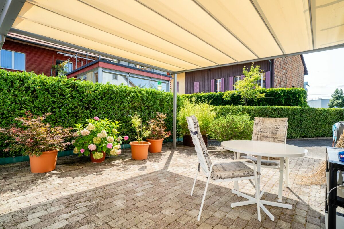 Überdachte Terrasse mit Sitzplatz und Gartenblick