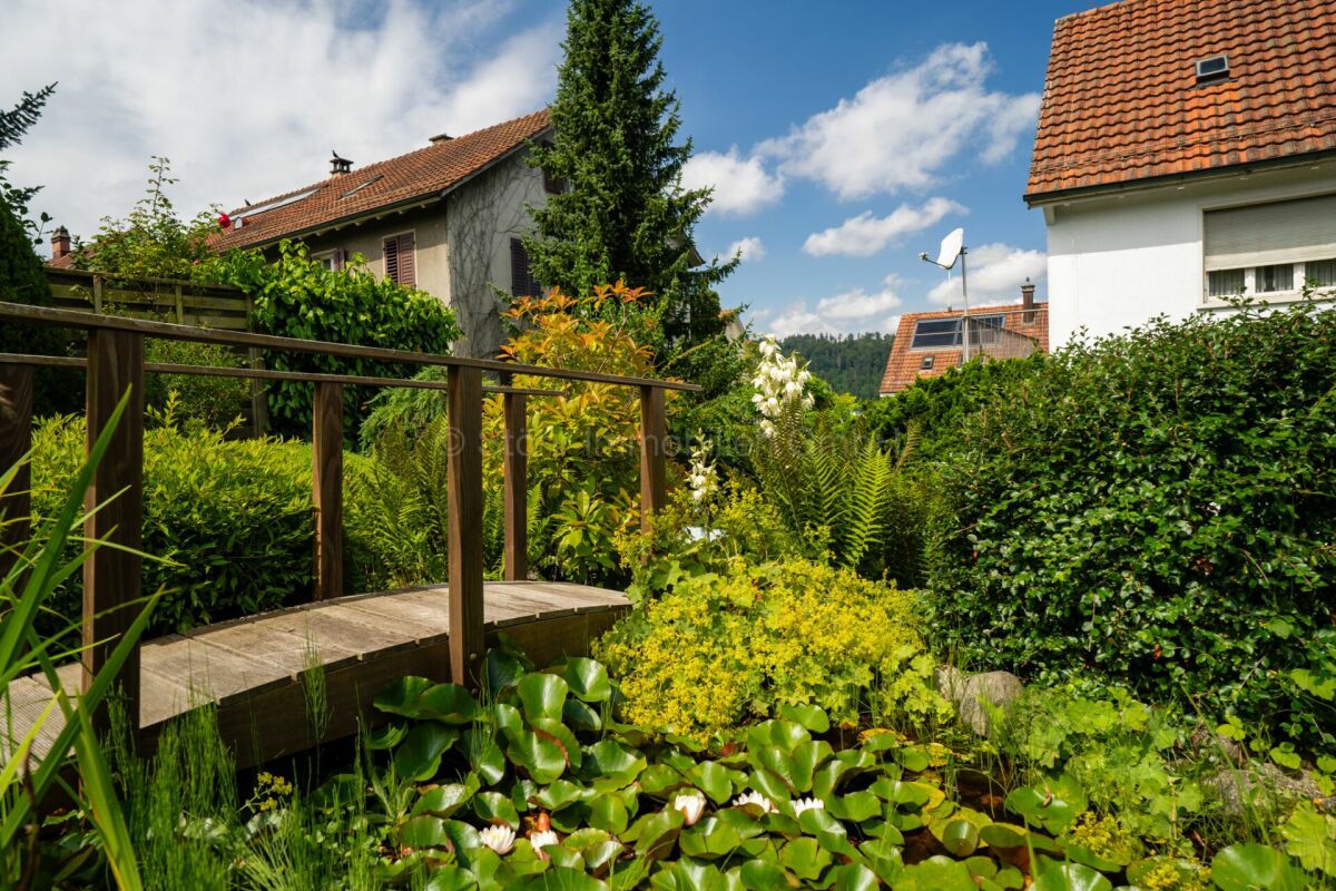 Garten mit Holzsteg und Nachbarhäusern