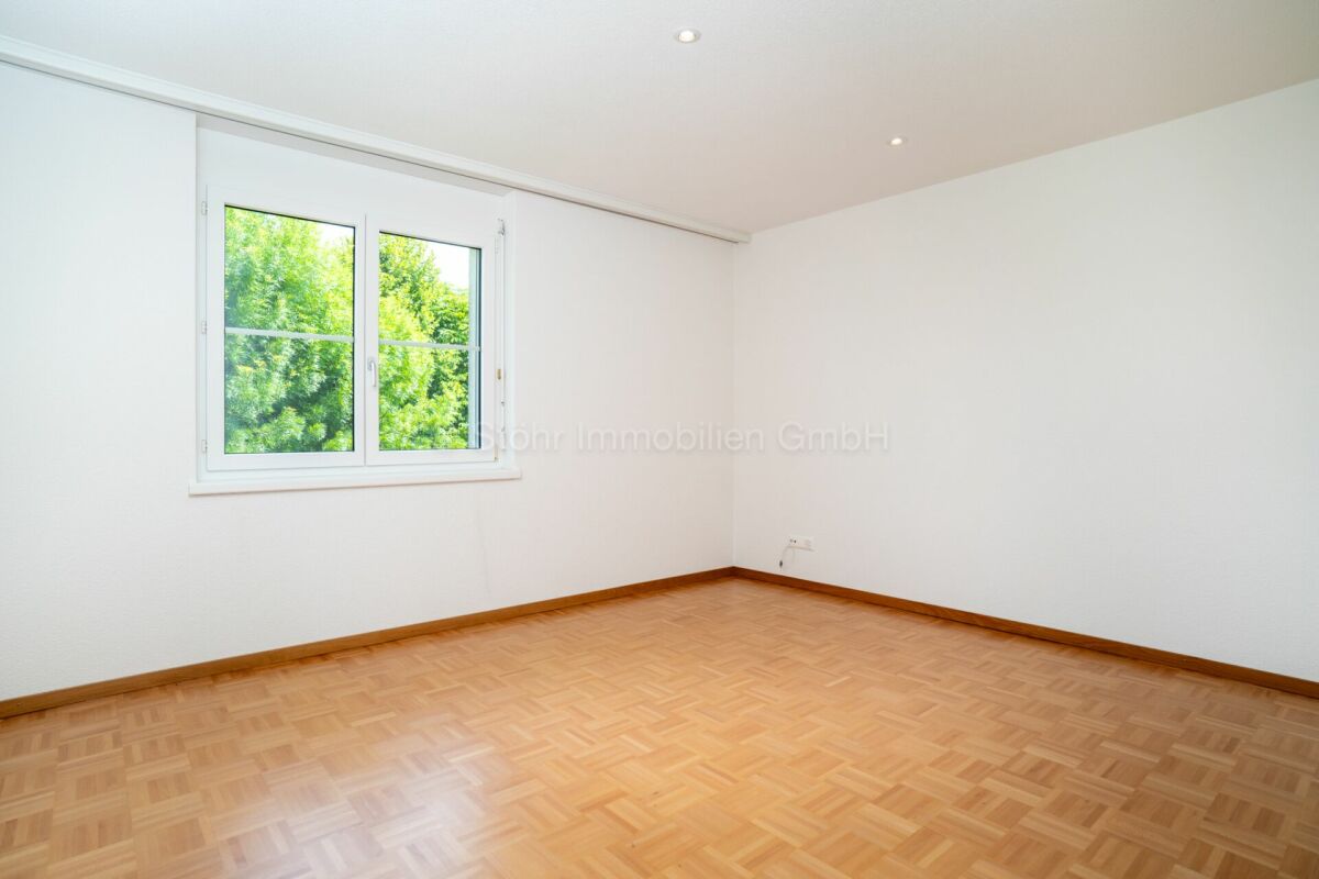 Leerer heller Raum mit Parkettboden und Fenster
