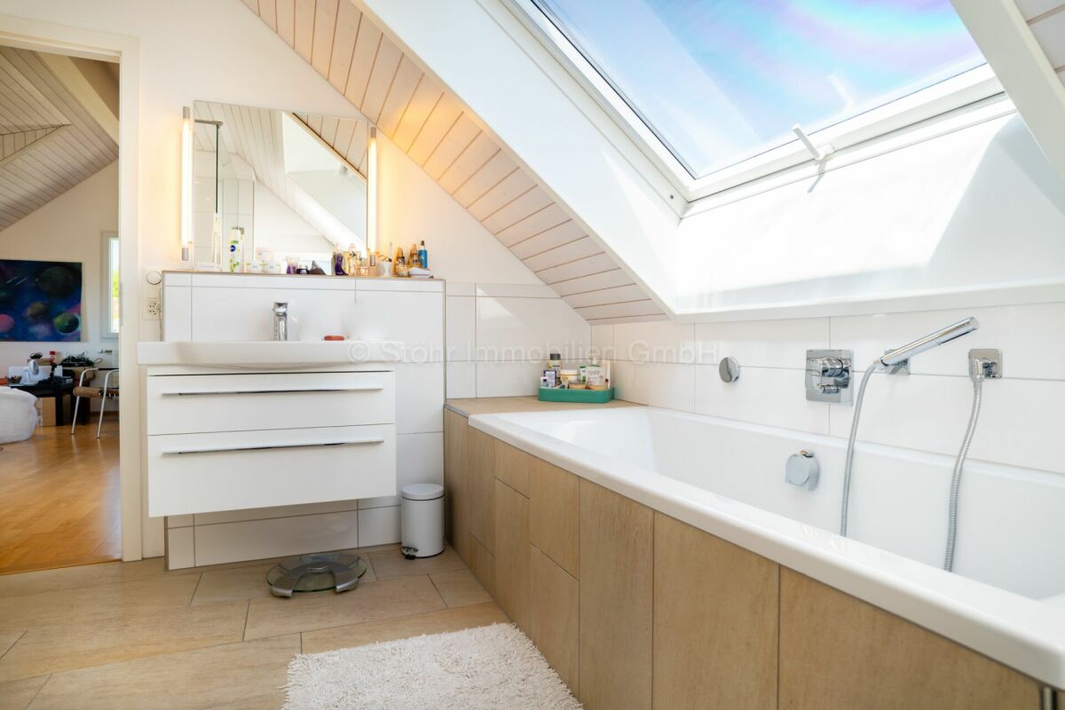 Helles Dachgeschoss-Badezimmer mit Badewanne und Dachfenster
