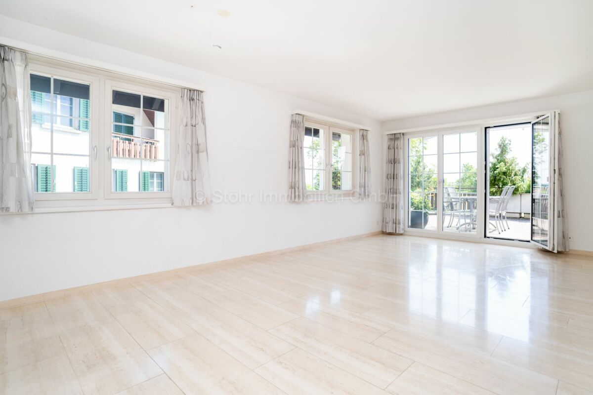 Heller leerer Wohnraum mit großer Fensterfront und Zugang zur Terrasse